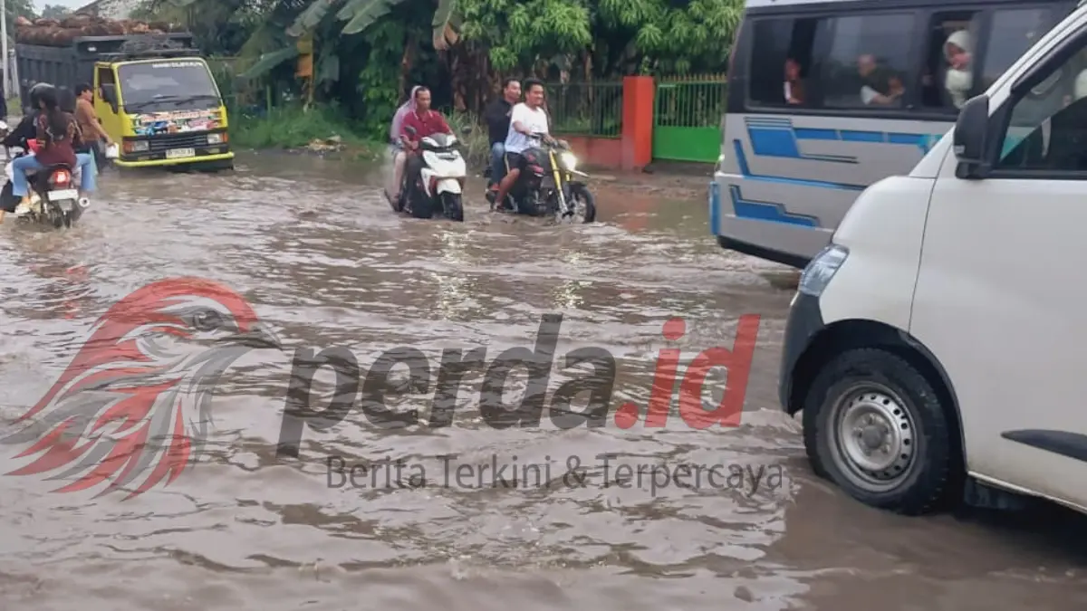 Kondisi jalan rusak parah di jalur lintas Perdagangan – Pematang Siantar yang digenangi air dan lumpur.